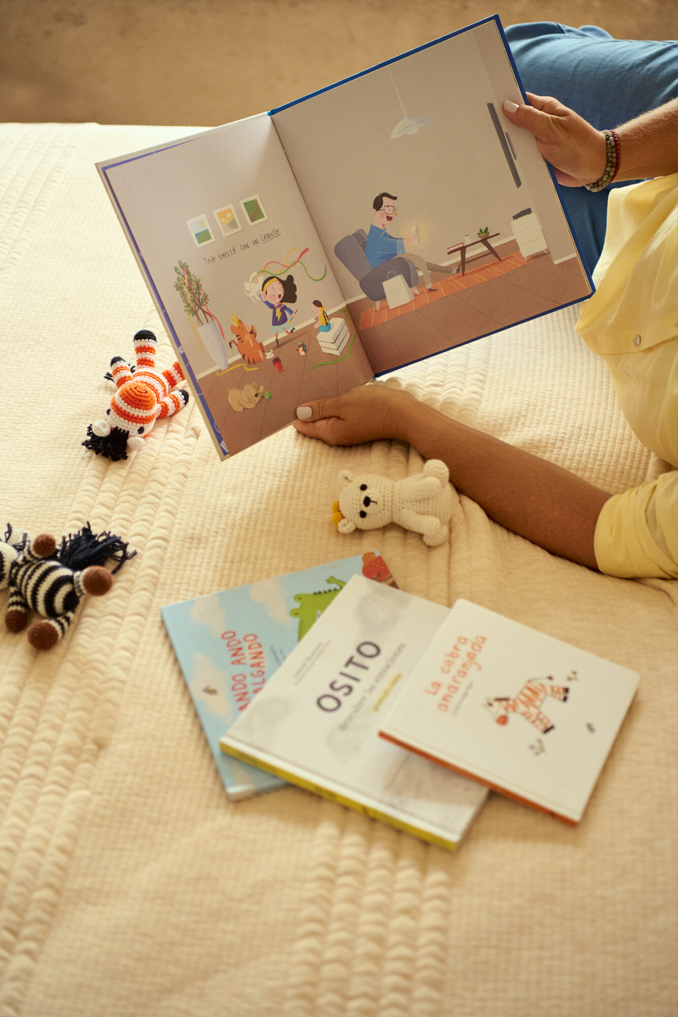 El catálogo de Zebra sobre la cama: un álbum abierto entre las manos, tres portadas y las cebras de crochet